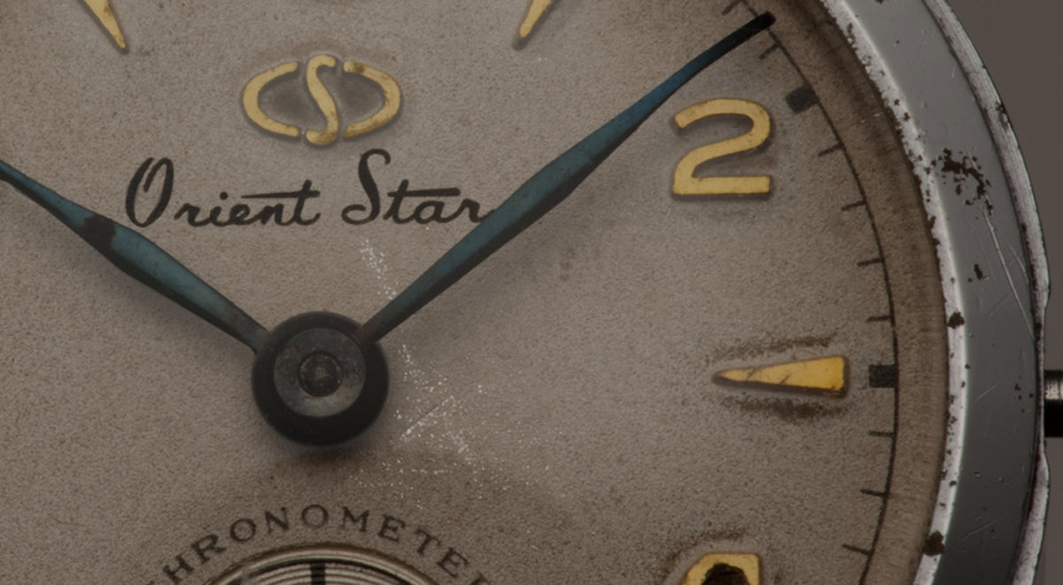 Close-up of an original 1951 vintage Orient Star Chronometer watch dial with gold Arabic numerals and aged patina