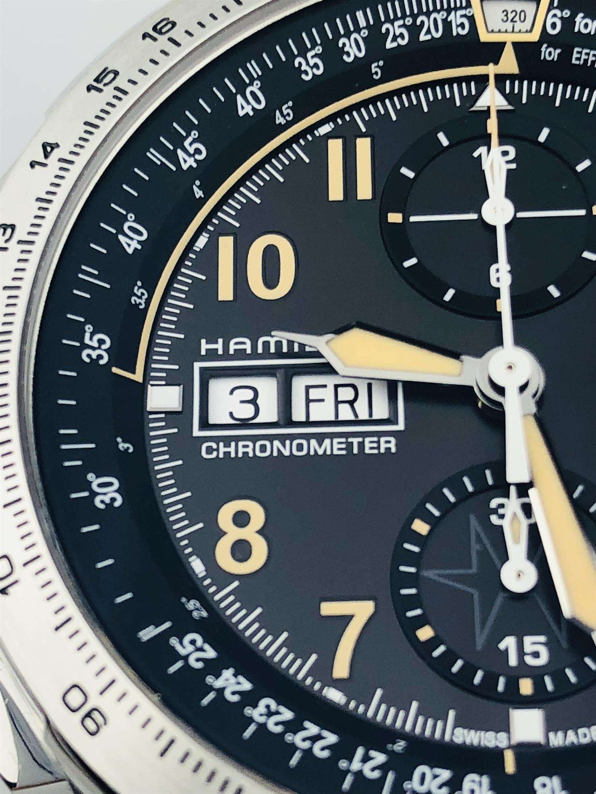 Close-up of men's chronograph watch dial, black with gold hour markers and fine subdial details