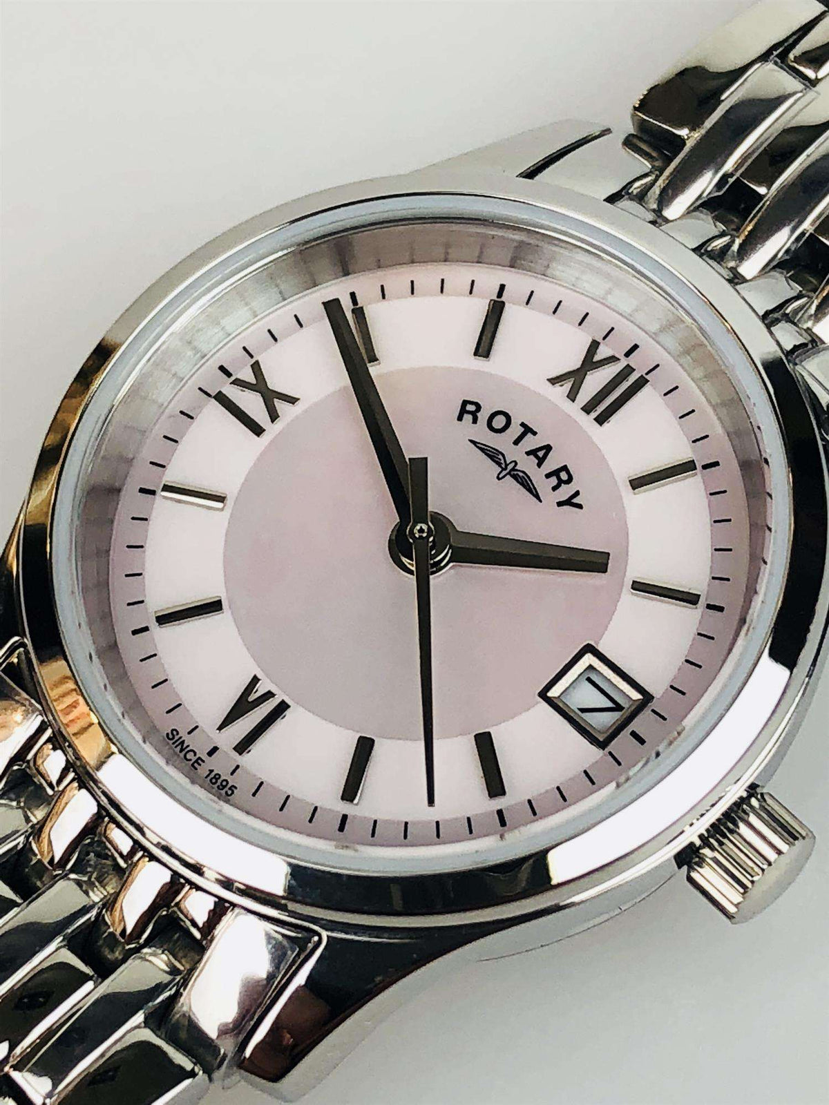 Round stainless steel watch face with mother-of-pearl dial, Roman numerals, and link bracelet