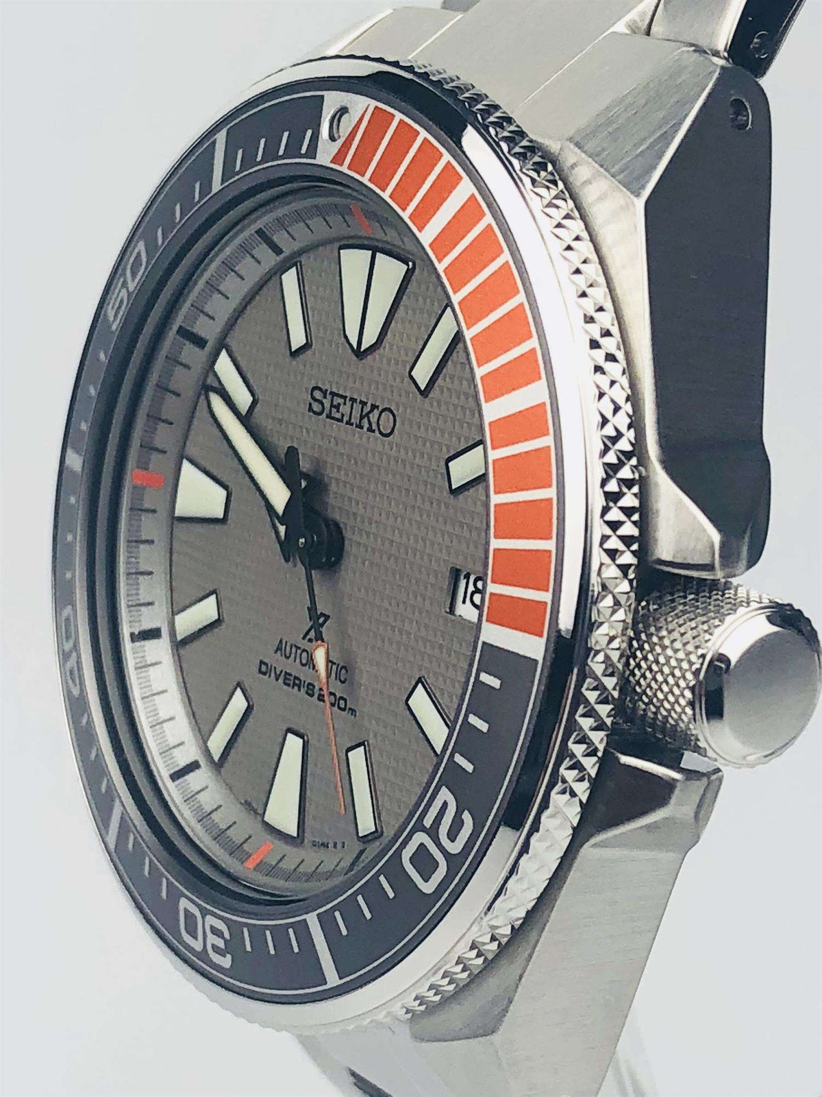 Men's stainless steel diver watch showing orange bezel insert and crown detail