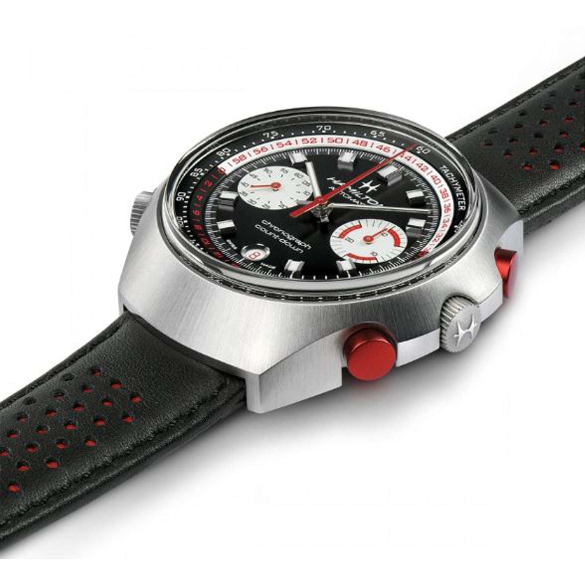 Close view of chronograph watch with black perforated leather strap, red crown, and black dial
