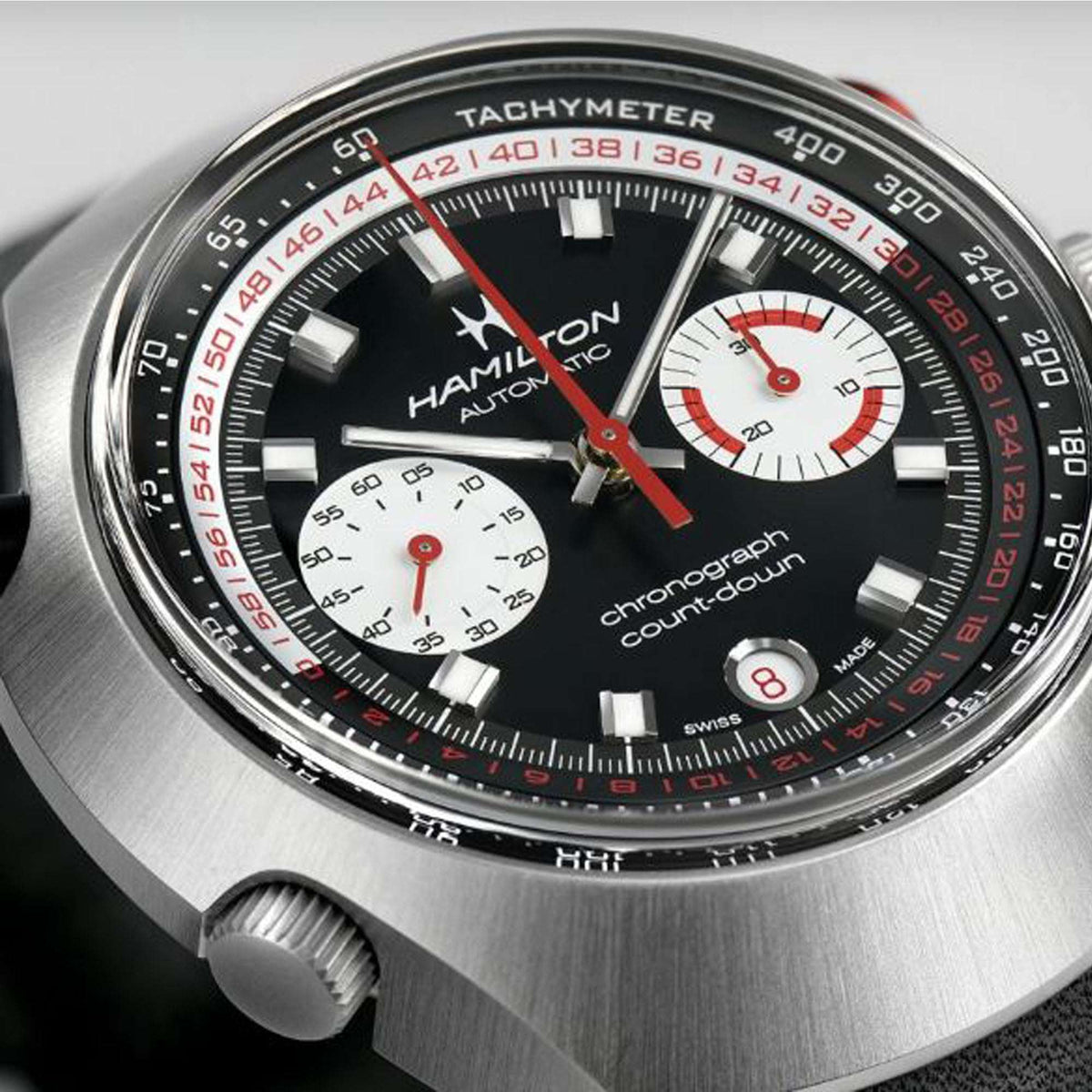 Close-up of automatic chronograph watch dial with tachymeter markings, black face, red hands