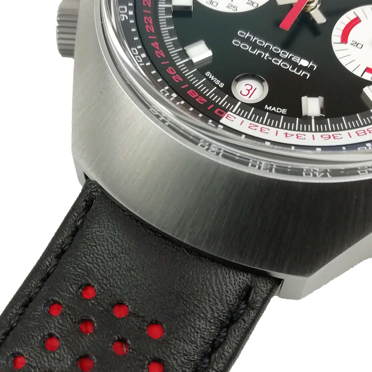 Close-up of men’s chronograph watch case and perforated black leather strap with red dots