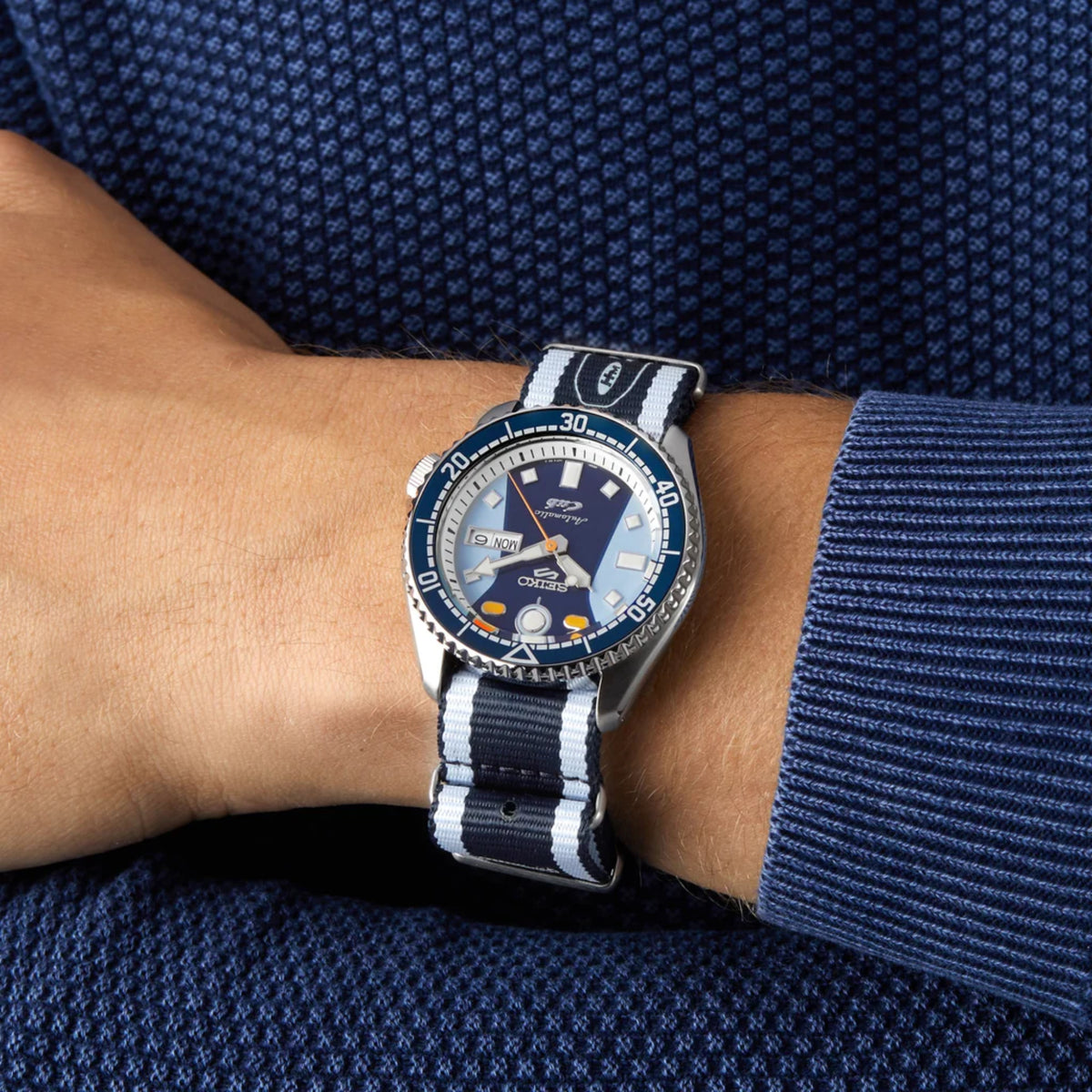 Automatic wristwatch with blue dial and blue-and-white NATO strap on wrist