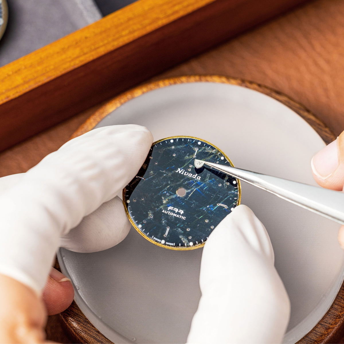 Nivada Grenchen F77 MK2 68054A77-DR watchmaker assembling labradorite dial with precision tweezers