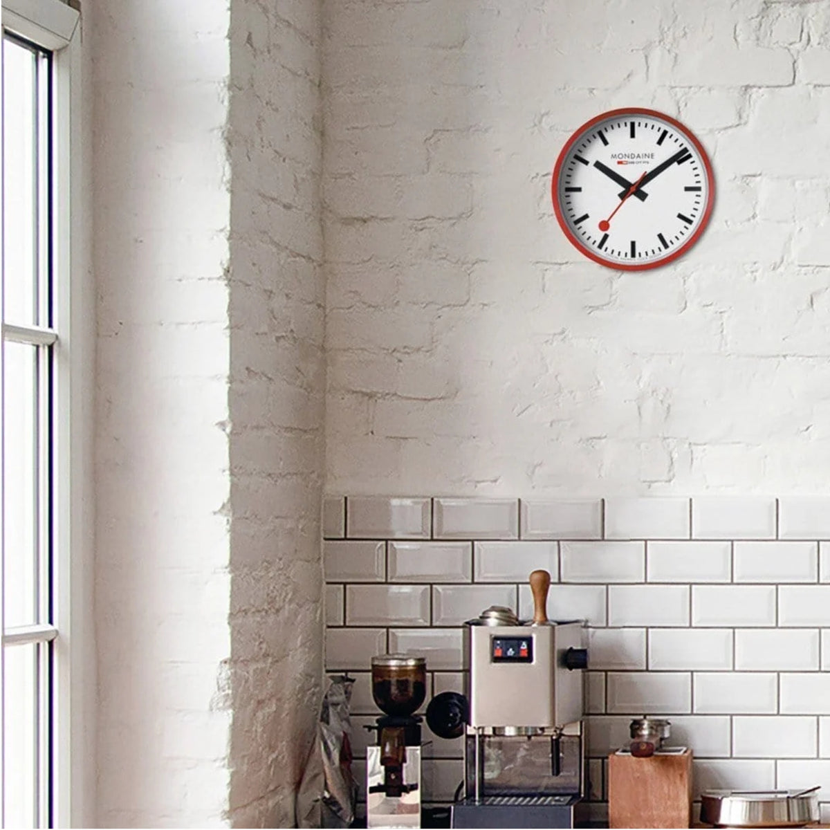 Mondaine quartz wall clock with white dial, black numerals, and red aluminum bezel