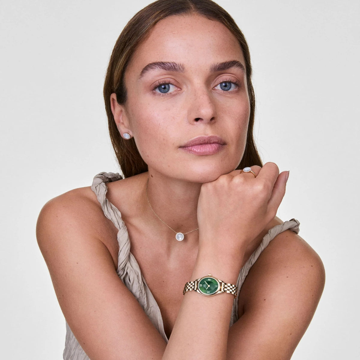 Green dial Daniel Wellington watch on model’s wrist with gold-tone link bracelet