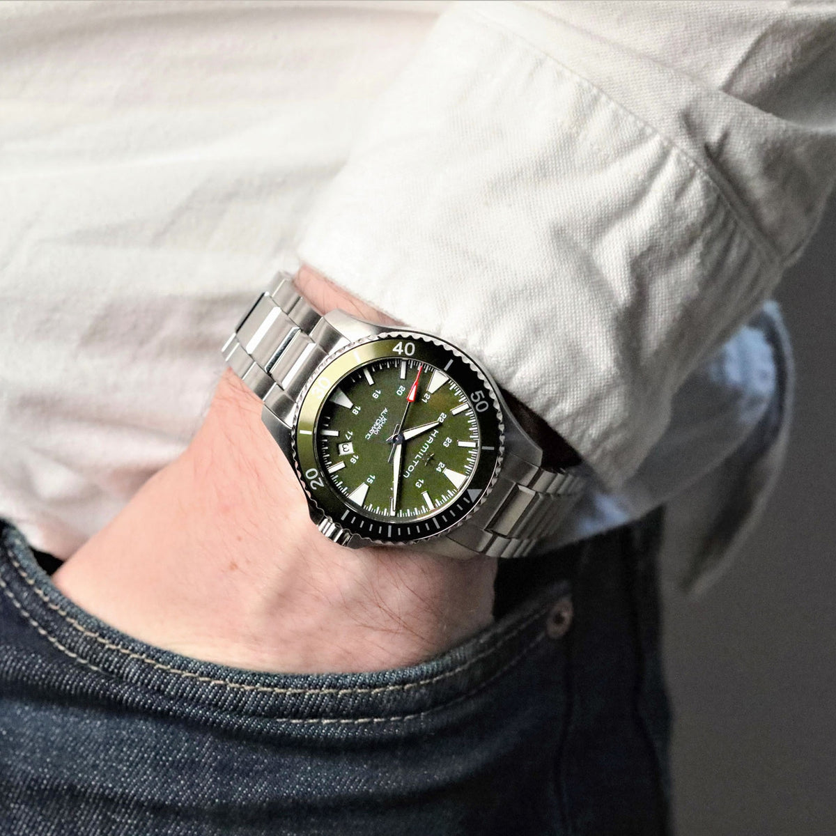 Men's Hamilton automatic watch on wrist with green dial and stainless steel bracelet