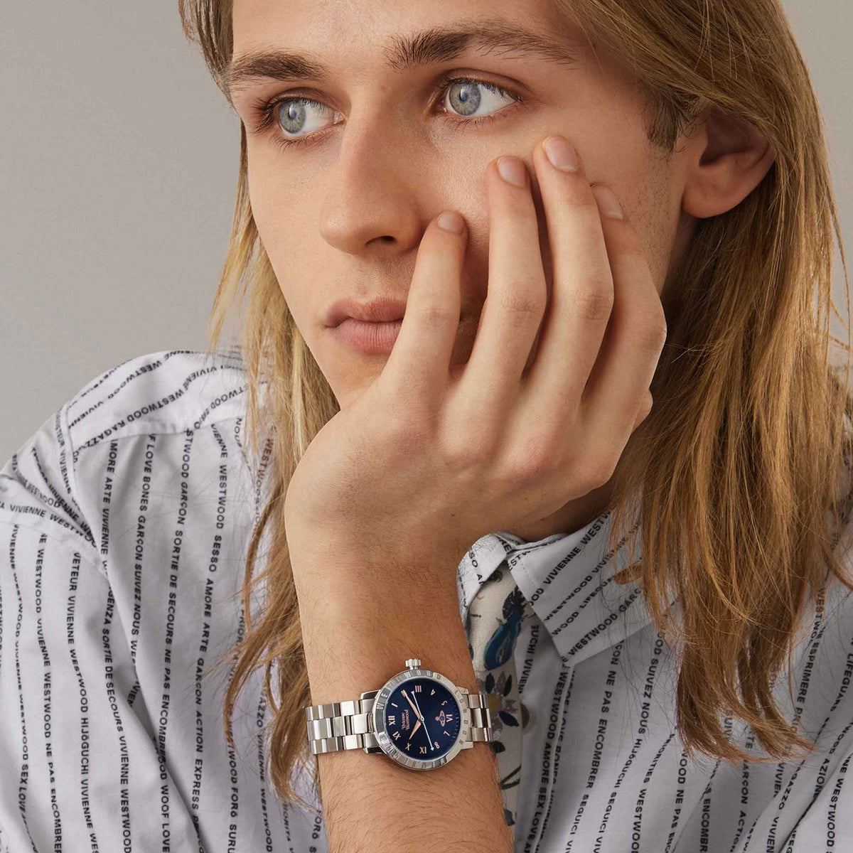 Women’s blue dial steel watch with Roman numerals, worn on wrist with long sleeves