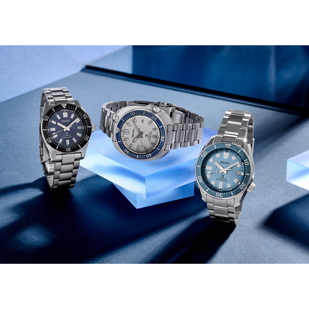 Set of men's automatic dive watches with blue bezels and stainless steel bracelets.