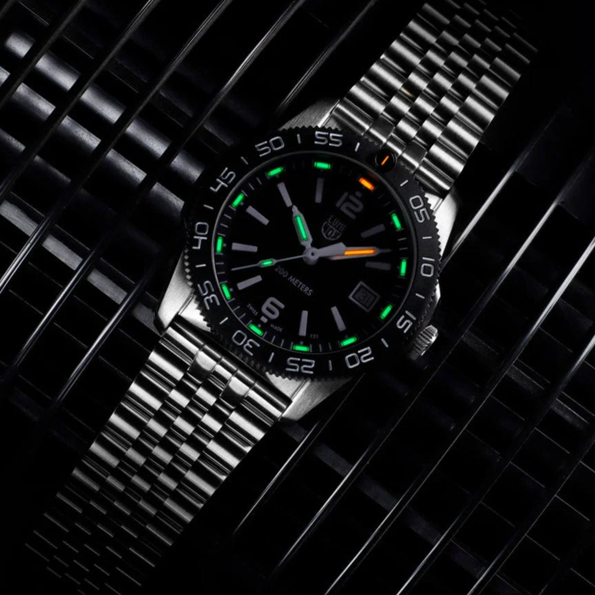 Silver metal diver watch with black dial and green luminous markers, date window