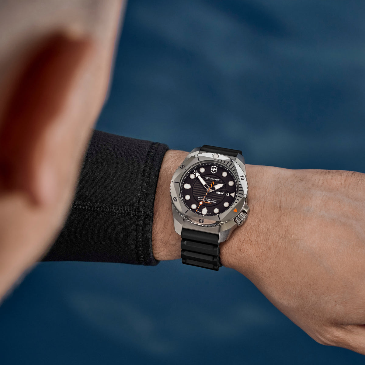 Men's automatic diving watch on wrist with black dial and black rubber strap