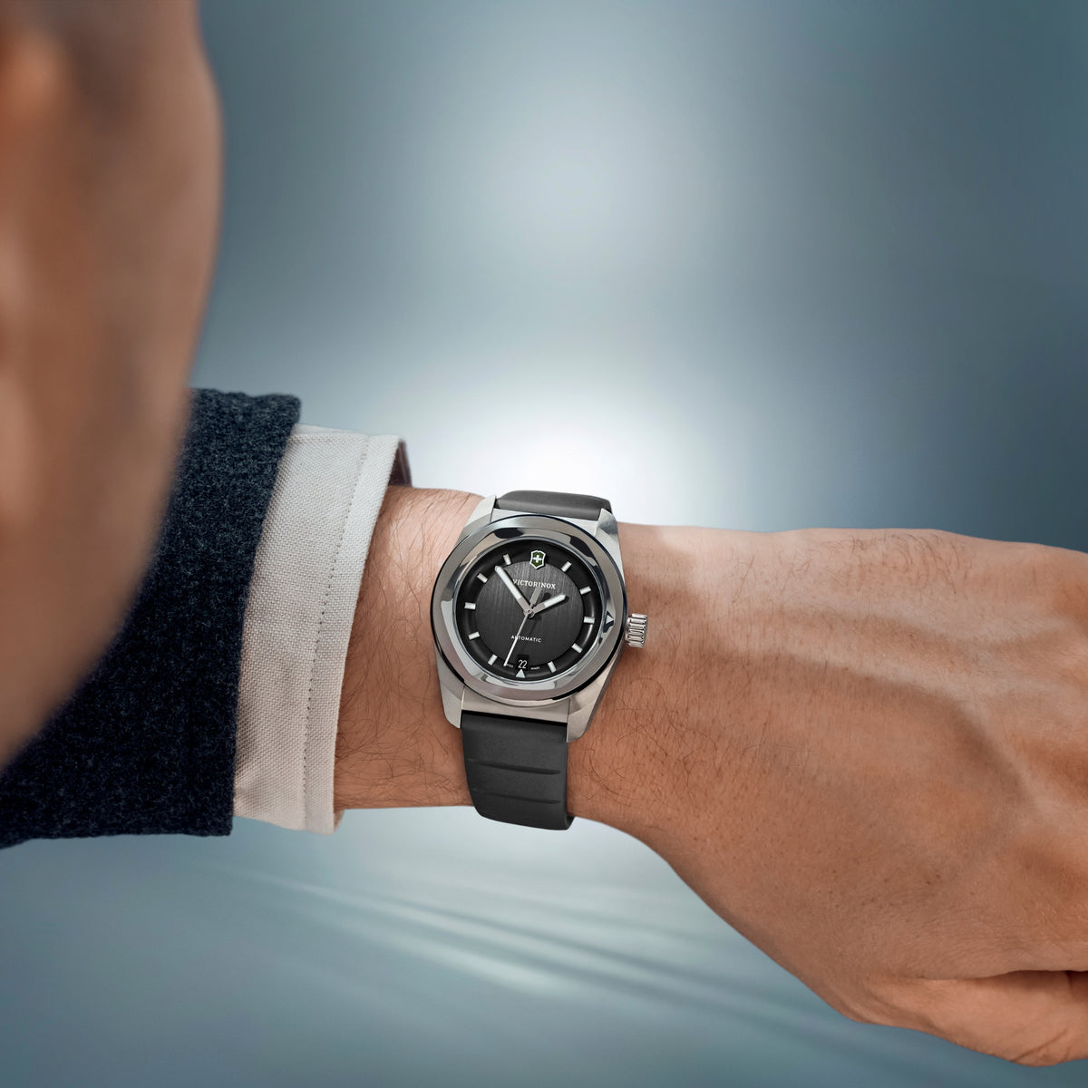Automatic watch on a man’s wrist with black dial and black rubber strap