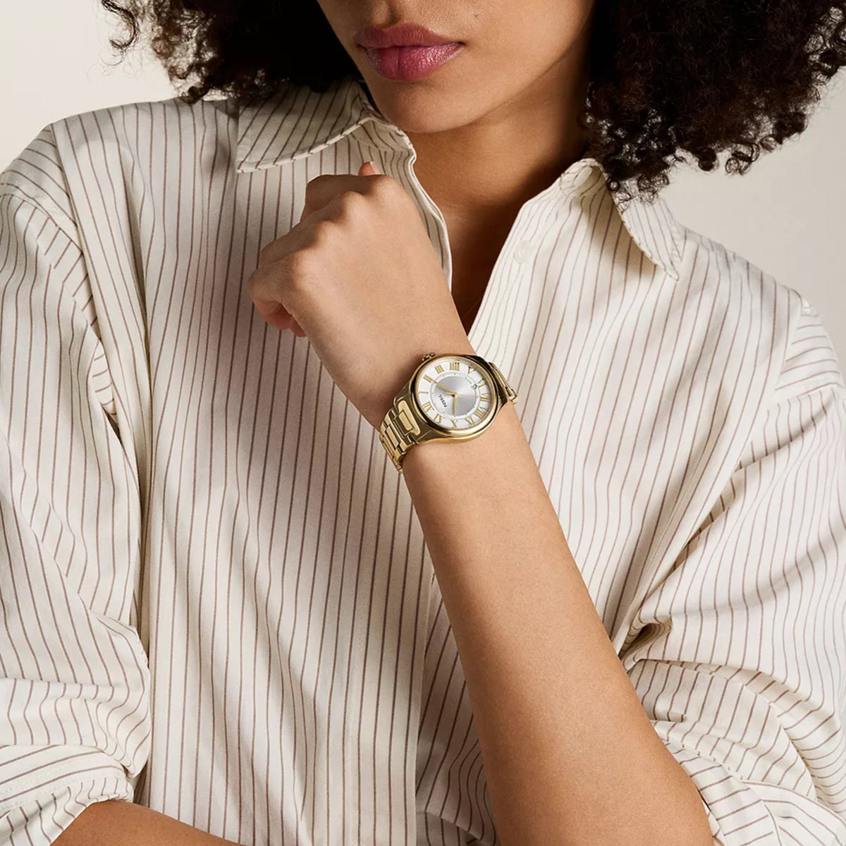 Gold-tone ladies quartz watch on wrist, round white dial with Roman numerals
