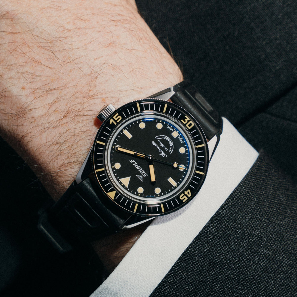Men's wristwatch with black dial, black rubber strap, and dark bezel on a forearm