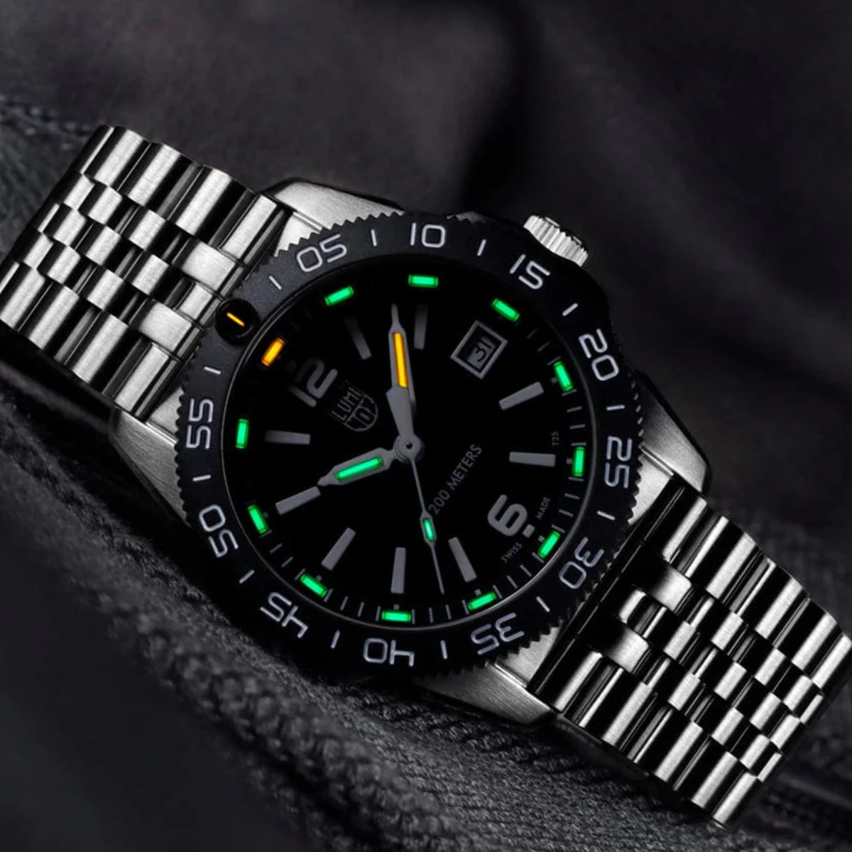 Stainless steel diver watch with black dial, green luminous markers, and luminous hands