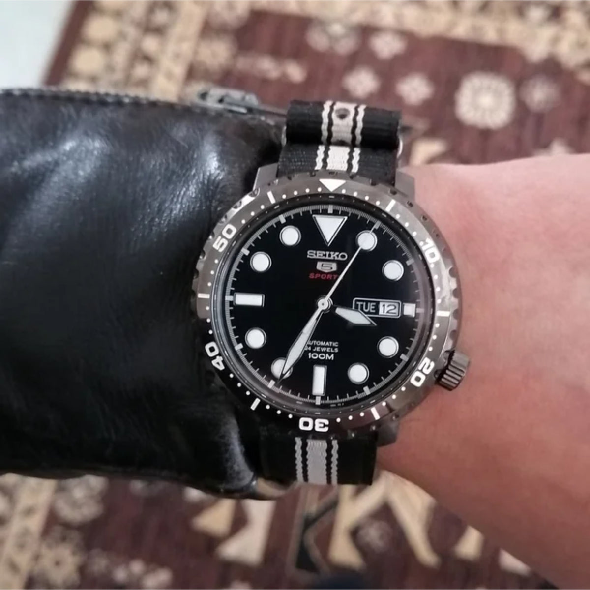 Men's wristwatch on black-and-white striped fabric strap with black dial and date window