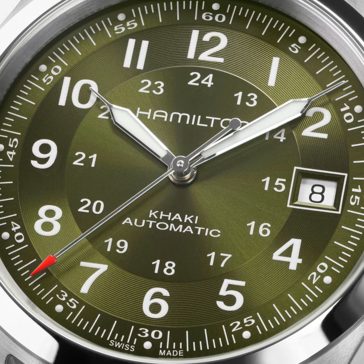 Hamilton Khaki Field H70455160 self-winding watch dial macro close-up showcasing luminous hands, Arabic numerals, date window, and green sunburst finish