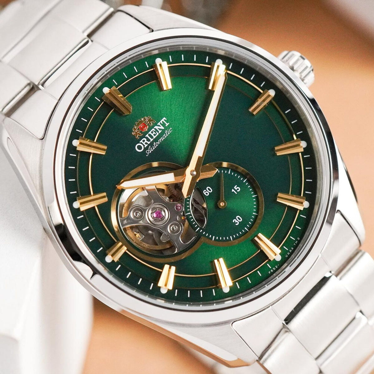 Close-up of the green sunburst dial face, open heart window, and gold-tone indexes on the Orient Semi Skeleton automatic watch