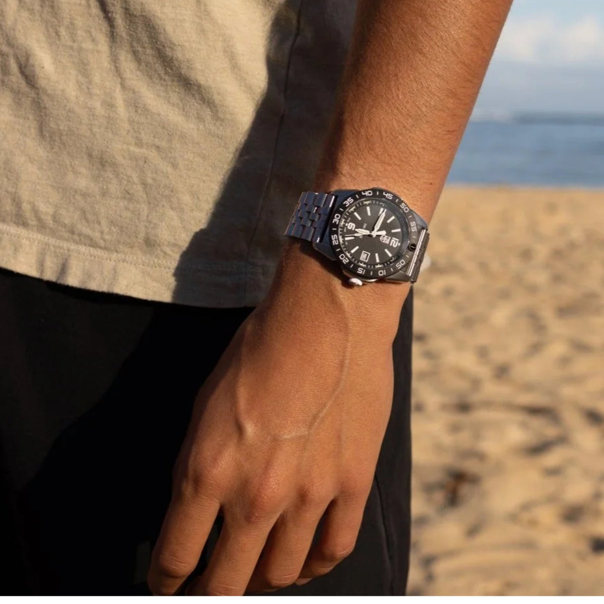 Men's black diver watch on wrist with black dial, luminous markers, and date window