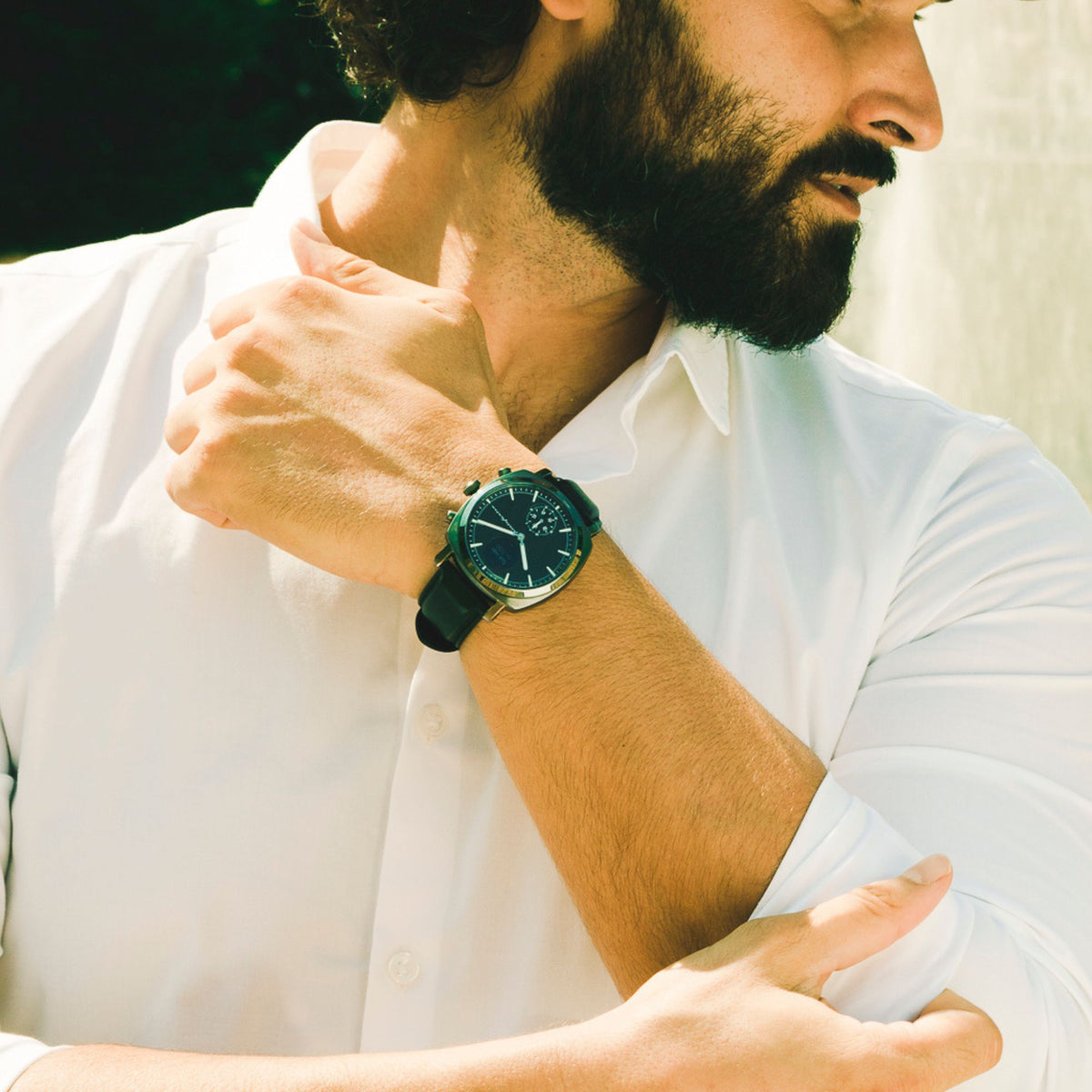 Hybrid smart watch worn on wrist with black leather strap and dark dial