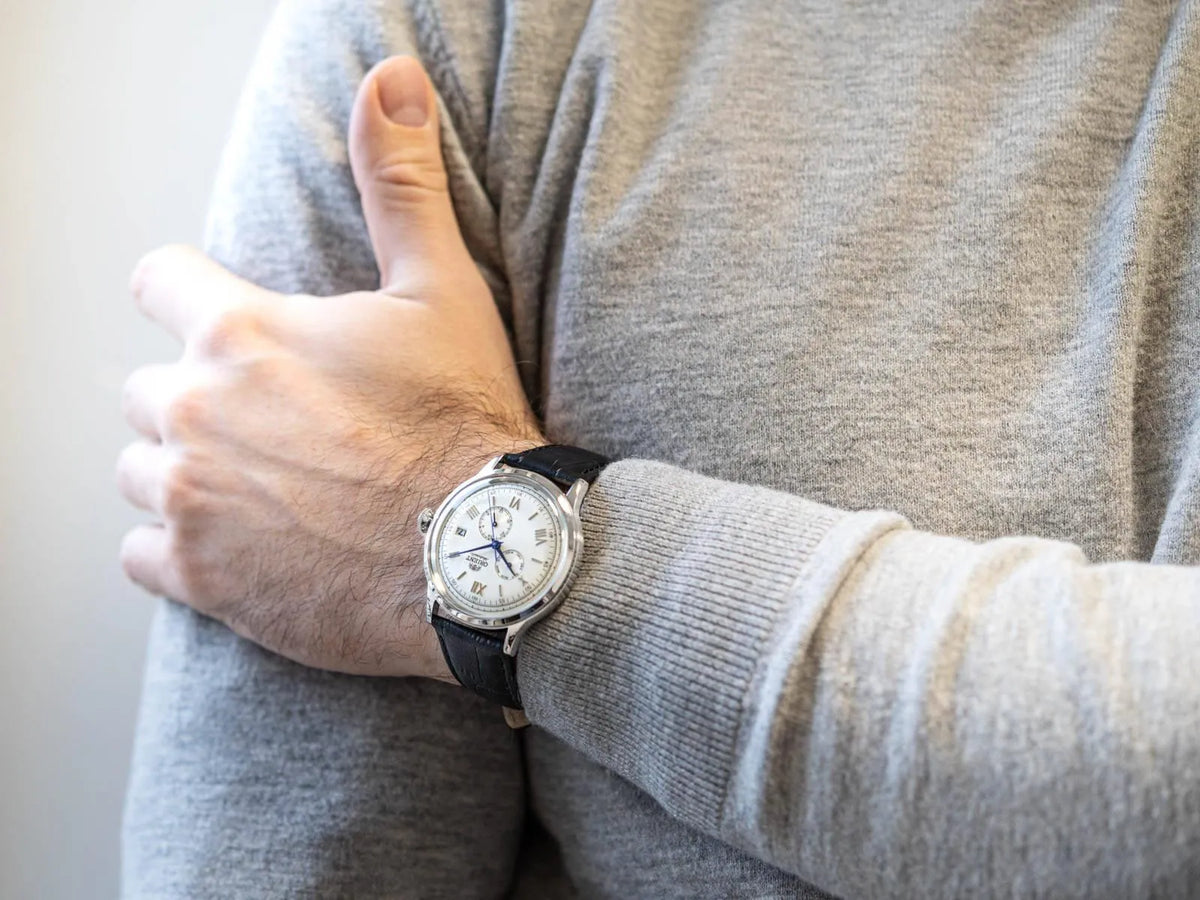 Orient Bambino RA-AK0701S30B mens timepiece with white dial and black leather strap worn on a wrist