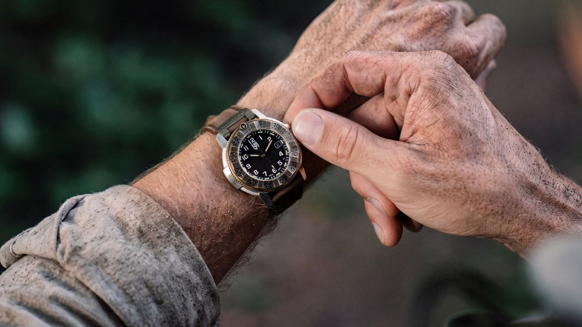 Luminox Adventure Watch XL.1301.LG, with its black dial and brown leather strap on a wrist, highlights its durable design in a natural environment