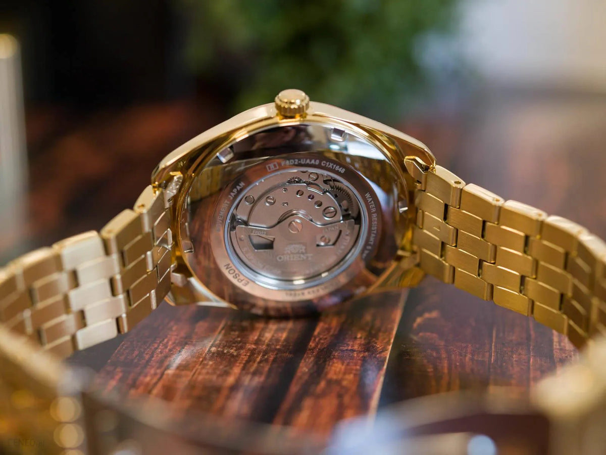 Men's automatic watch with open caseback showing movement, gold-tone steel bracelet