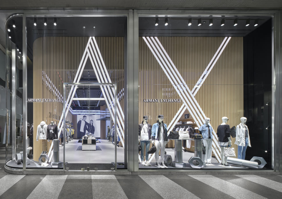 Armani Exchange retail store facade featuring large illuminated AX logo design and fashion mannequins