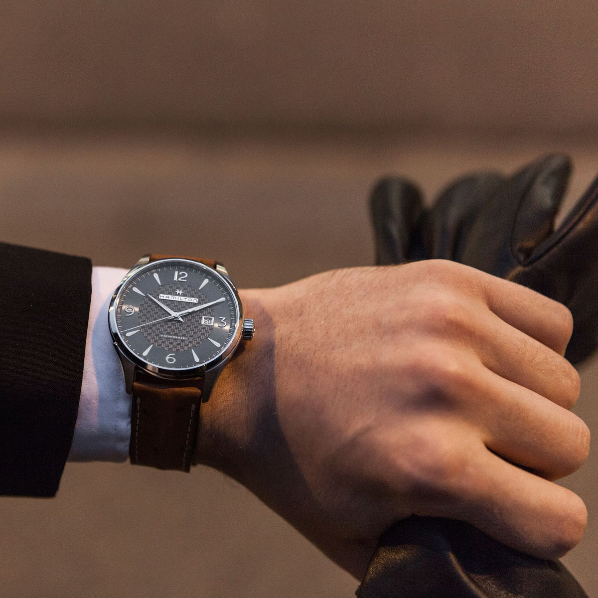 Men's automatic watch worn on wrist, grey dial and brown leather strap