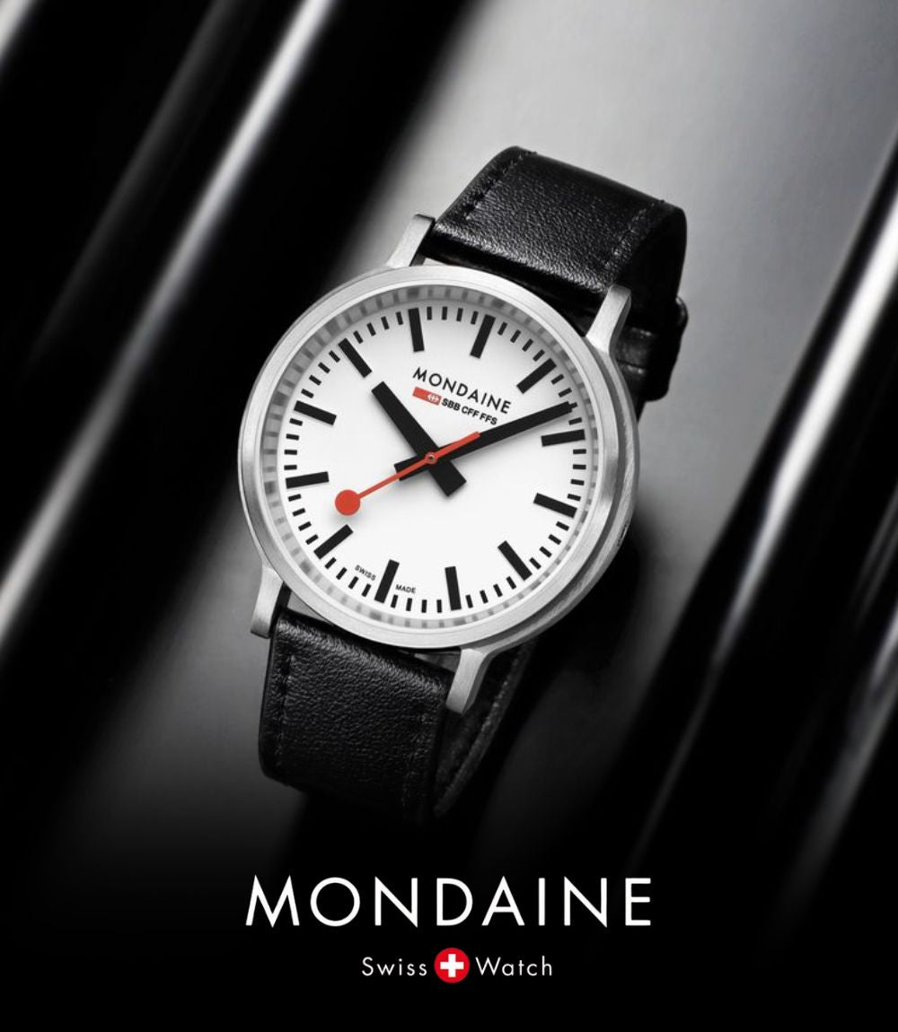 Mondaine Swiss Railway wrist watch resting on a reflective black background, featuring a minimalist white dial with thick black indices, bold black hands, and a signature red round seconds hand, paired with a black leather strap, featuring the Mondaine logo at the bottom