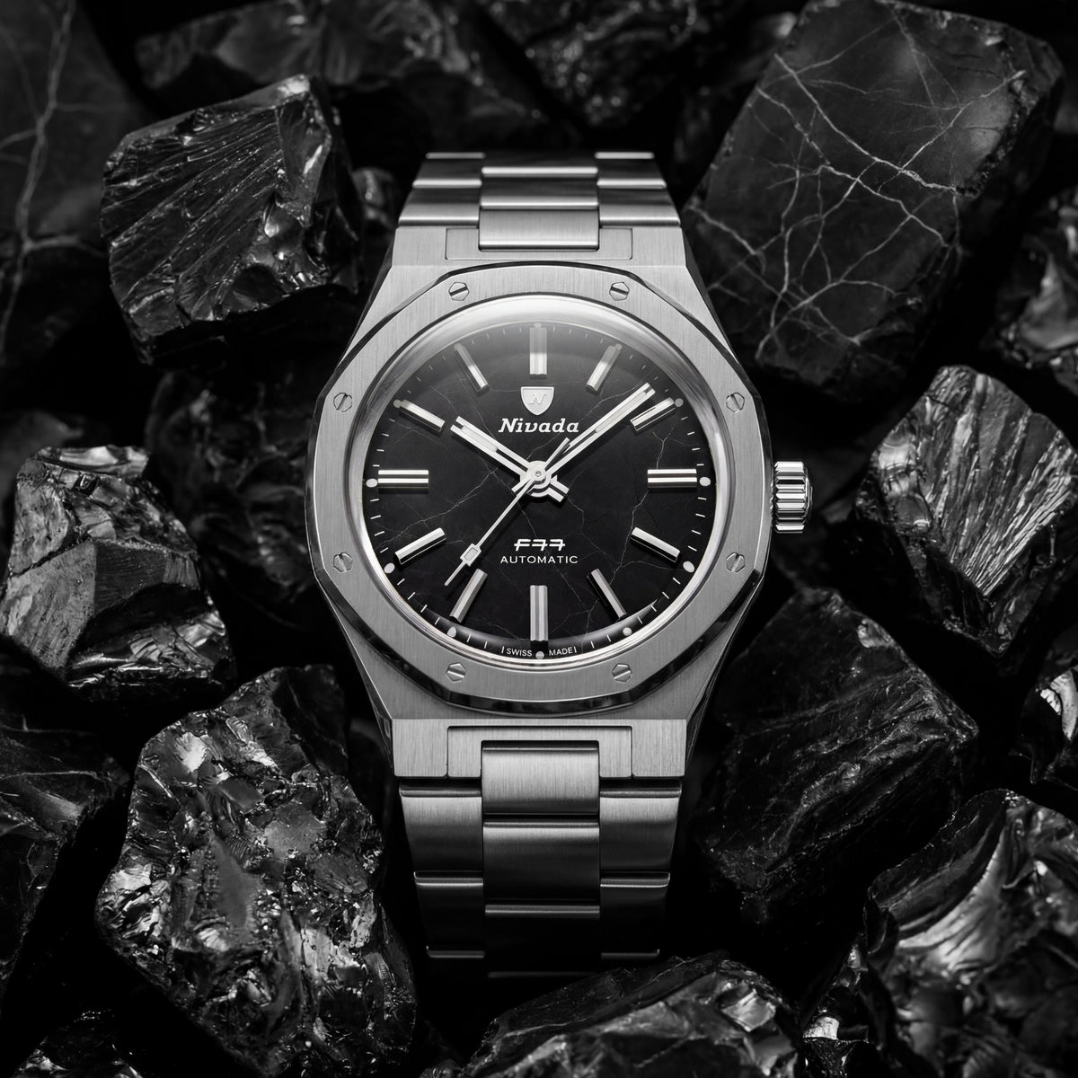 Nivada Grenchen F77 68058A77 front view resting on raw stone displaying shungite black dial and steel case