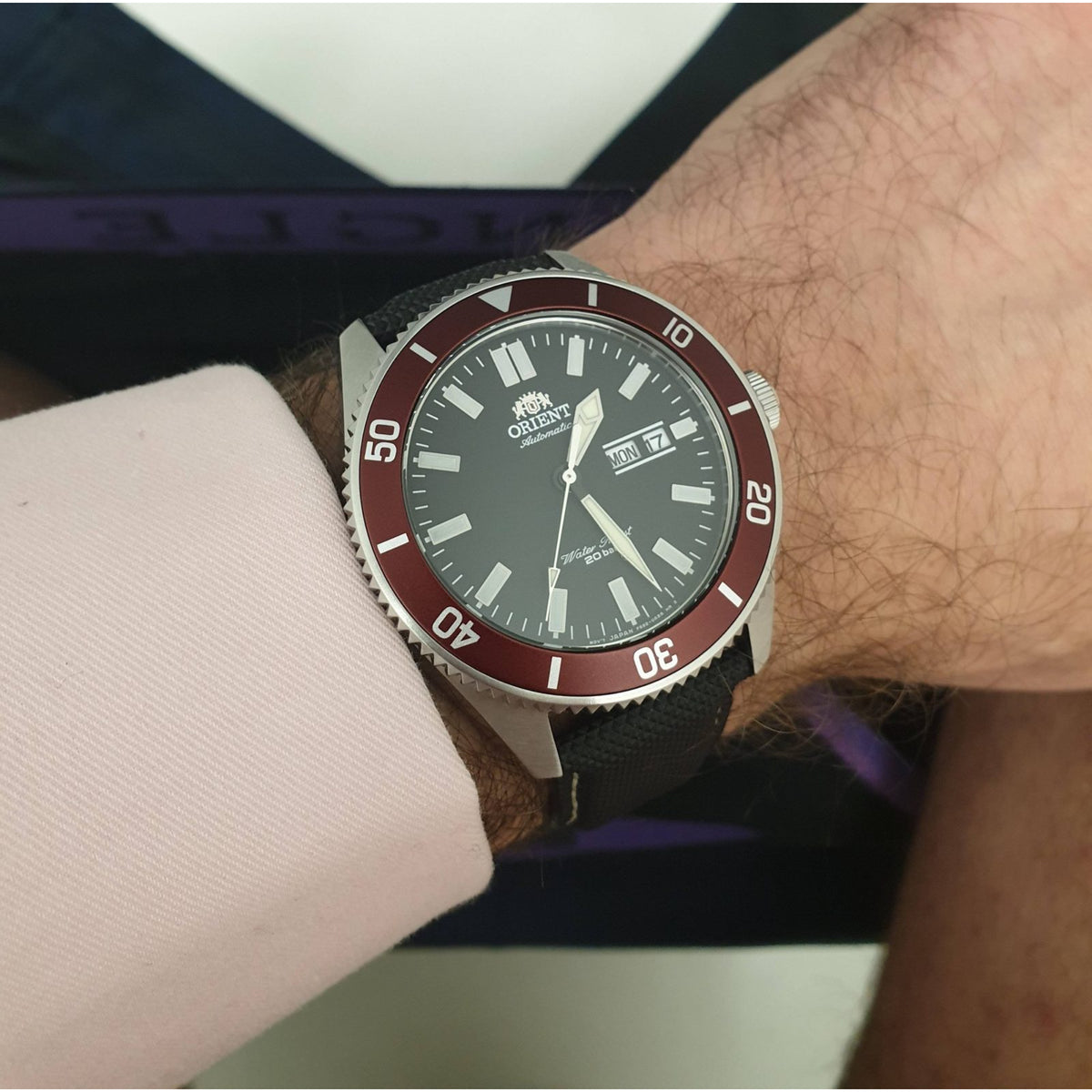 Men's automatic dive watch with black dial, red bezel, black silicone strap.