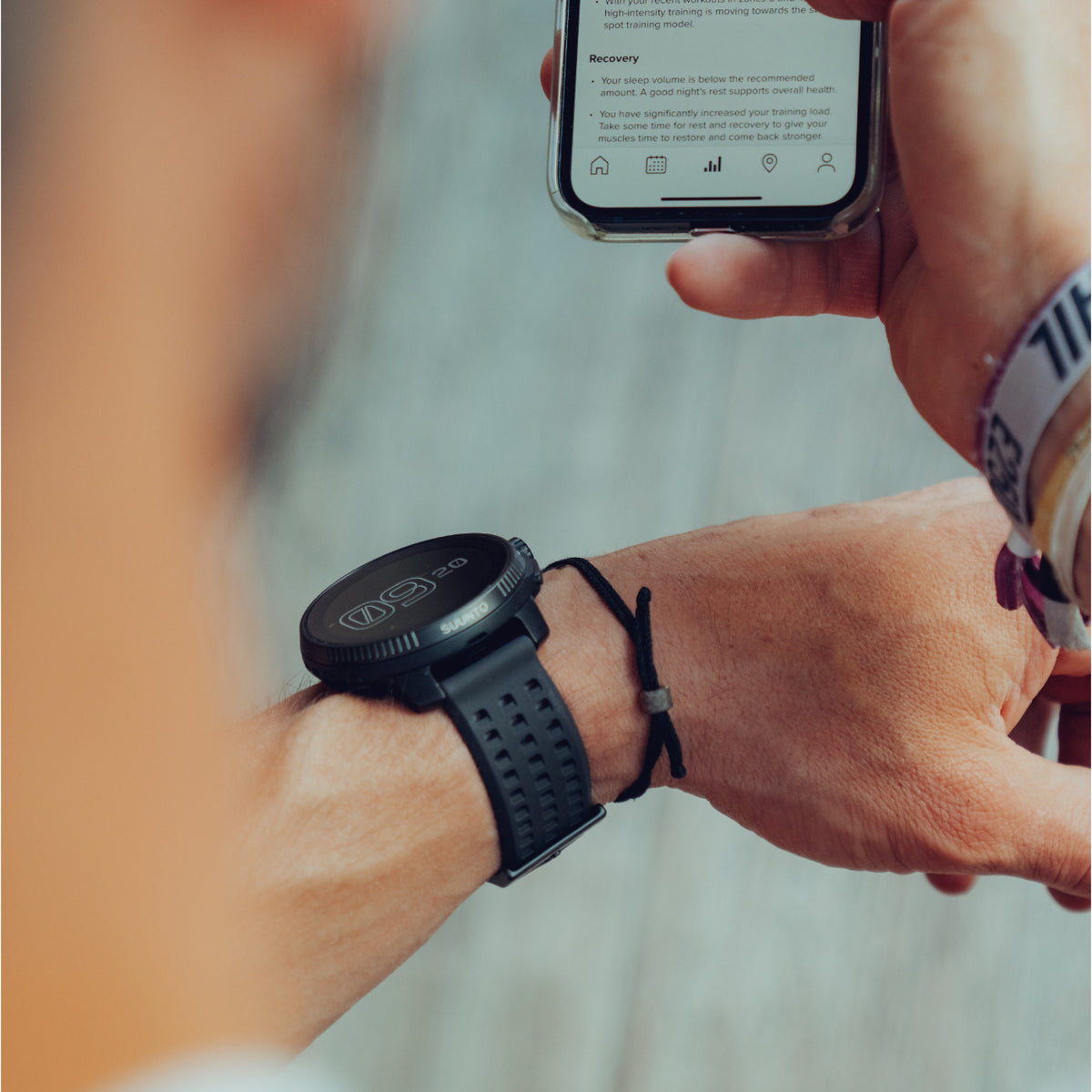Close-up of black Suunto GPS sports watch on wrist syncing sleep and training data to smartphone