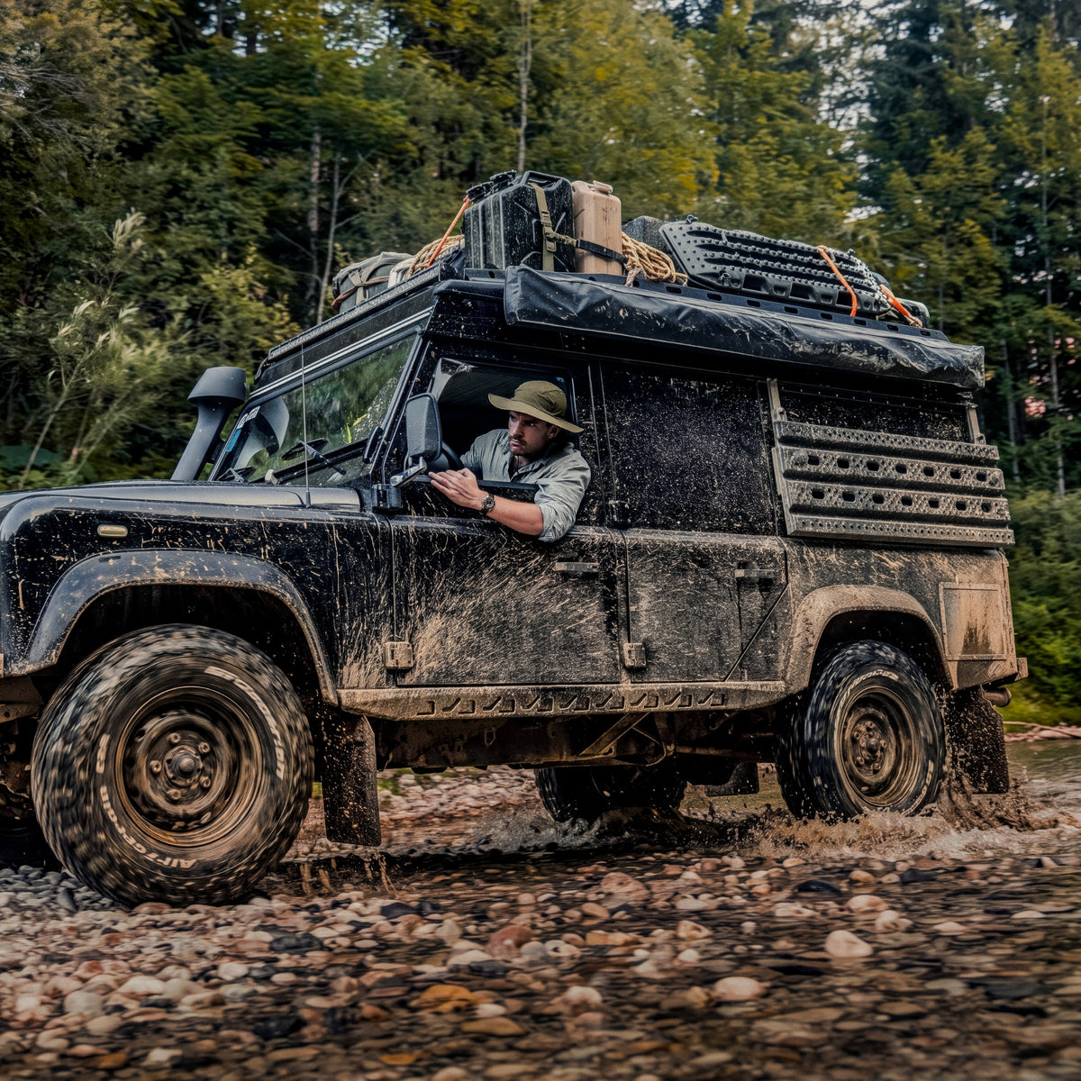 A muddy off-road vehicle driving through a rocky riverbed, with the driver wearing a Luminox Adventure Watch XL.1301