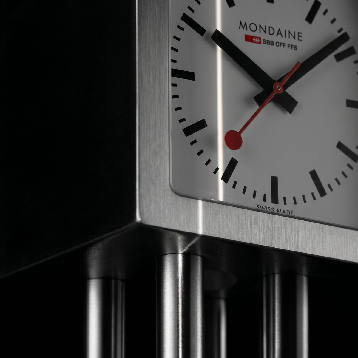 Aluminum table clock dial close-up with black markers and red second hand