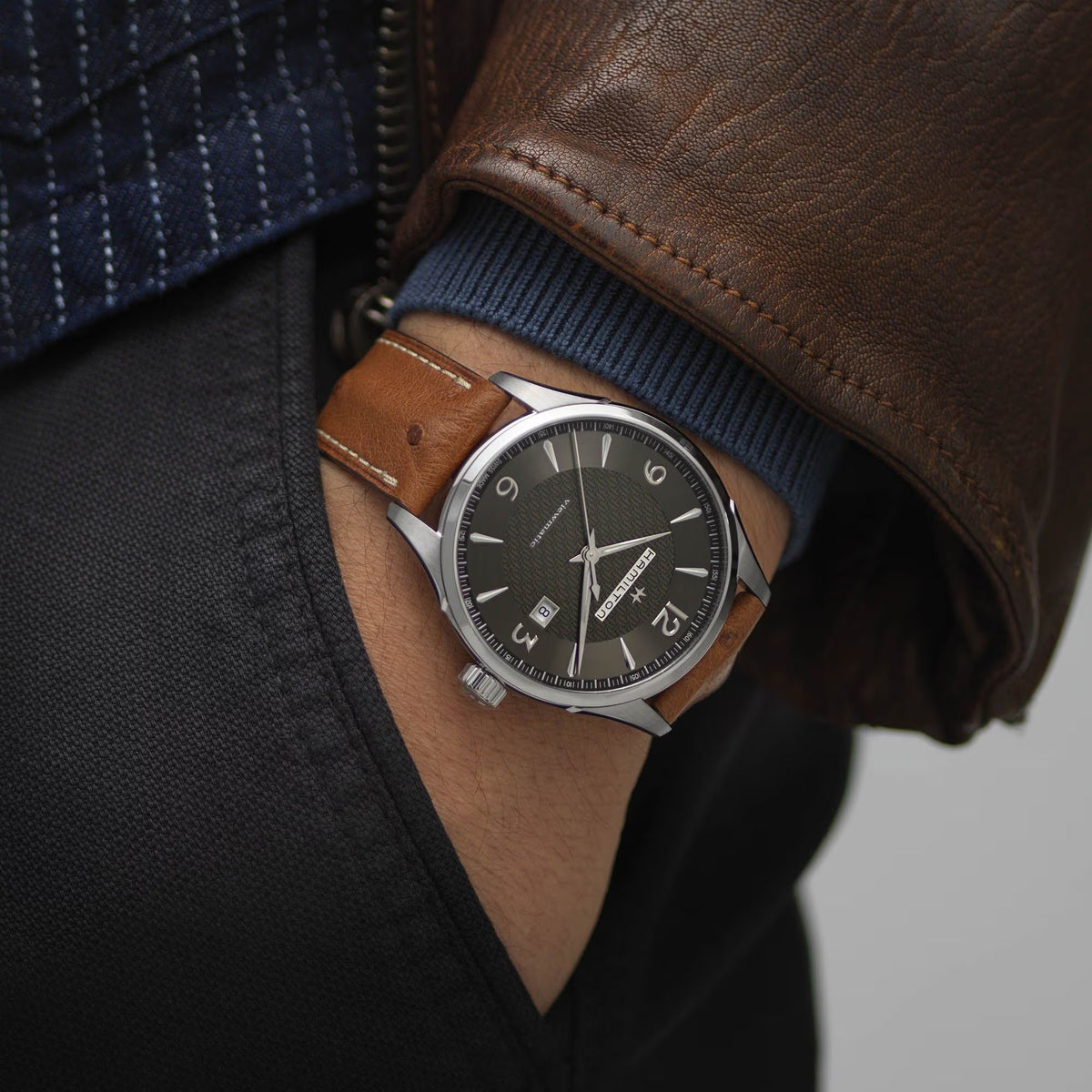 Men's automatic watch on arm with brown leather strap and grey dial