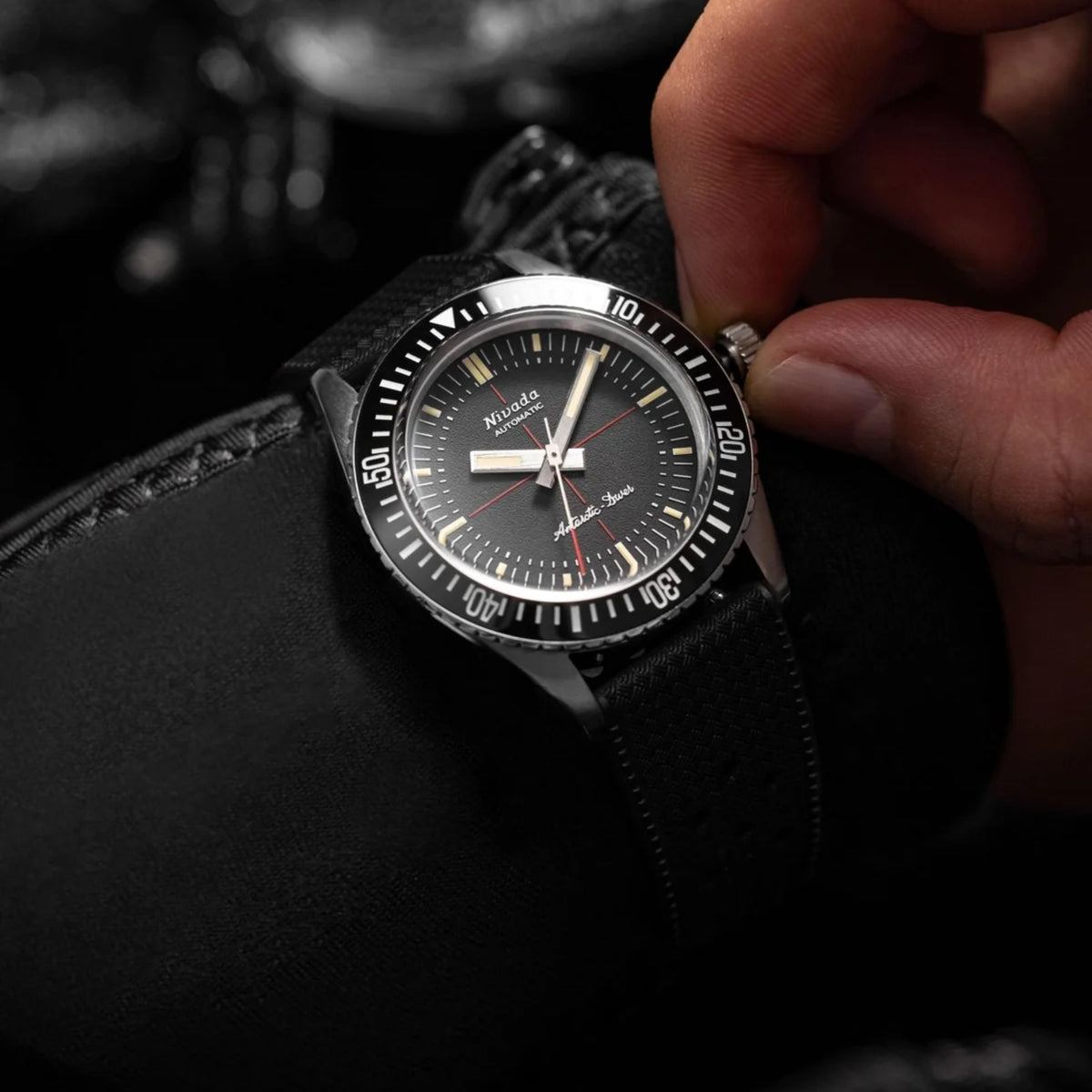 Black diver watch on black rubber strap with crosshair dial and bold hour markers