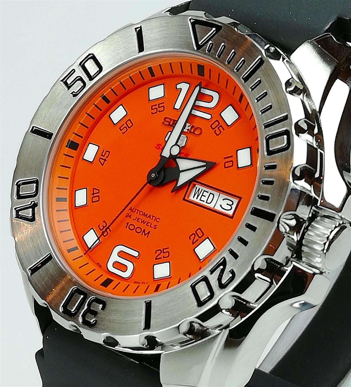 Close-up of orange dial sports watch with steel bezel and day-date window