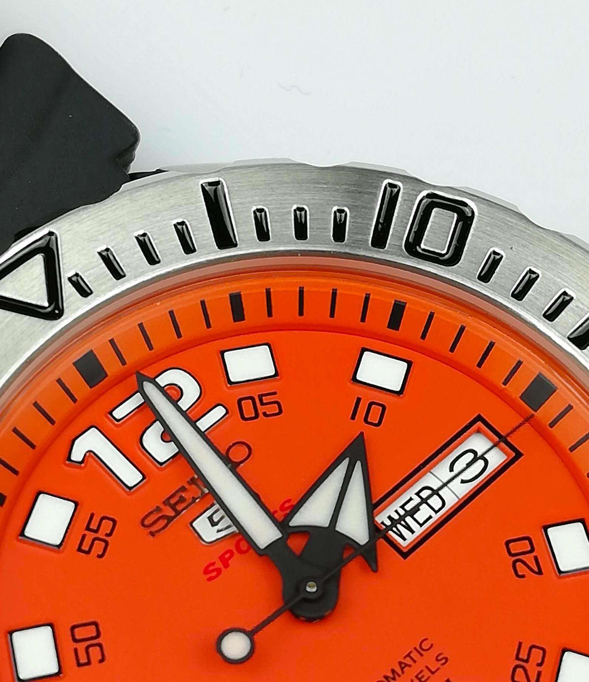 Orange dial sports watch with baton markers and day-date window on metal bezel