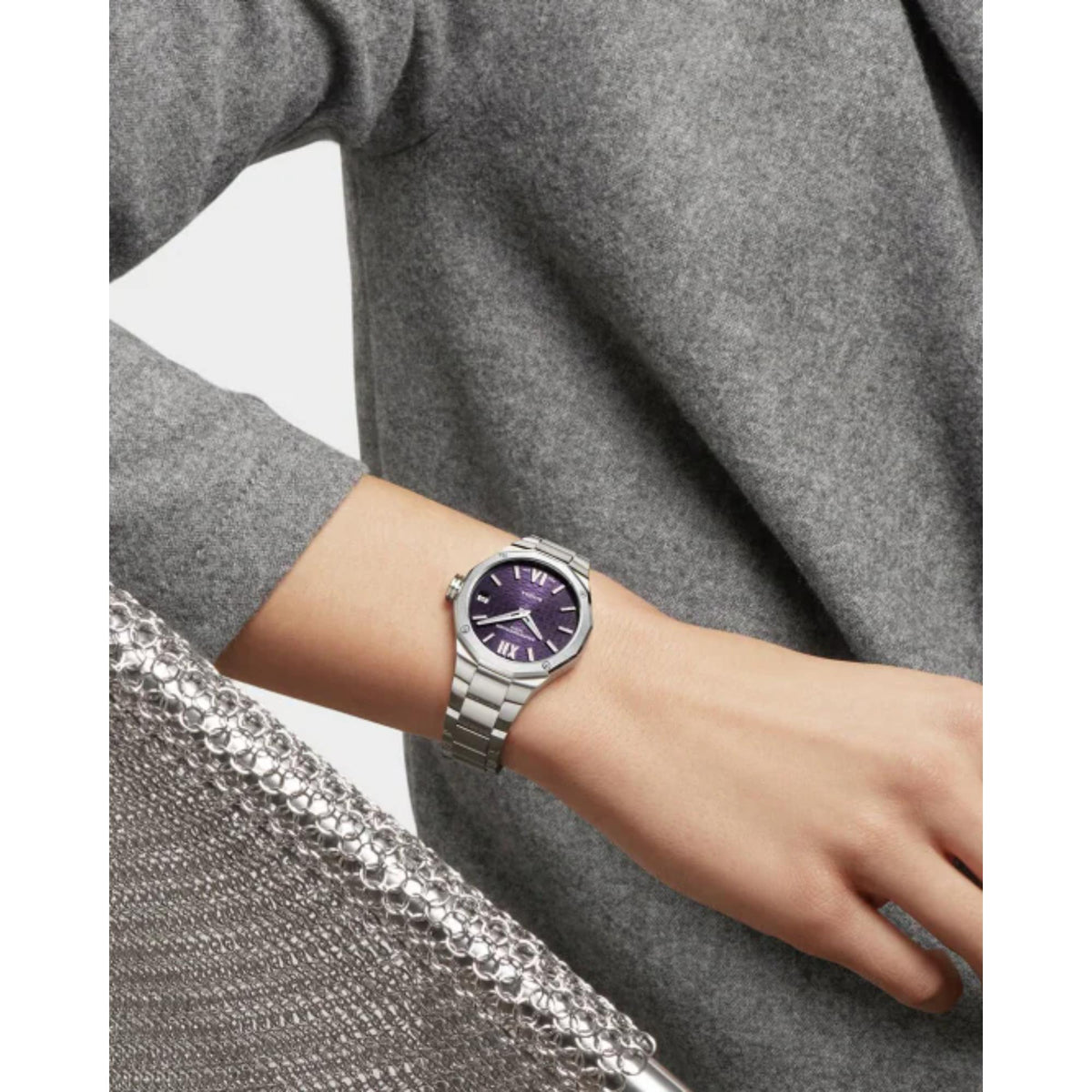 Women's steel watch on wrist with purple dial and segmented metal bracelet