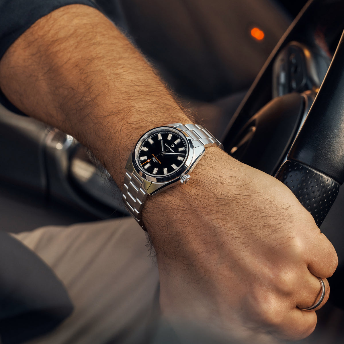 Men's steel bracelet automatic watch with black dial and silver hands, worn on wrist