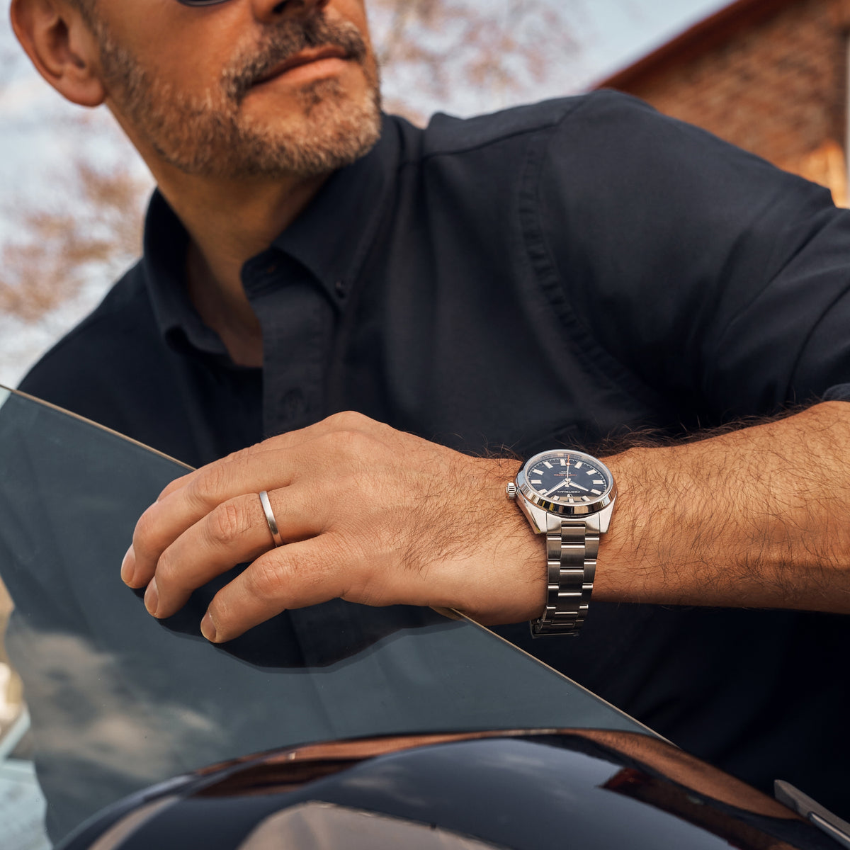 Men's automatic wristwatch with black dial and steel link bracelet, on a man's wrist