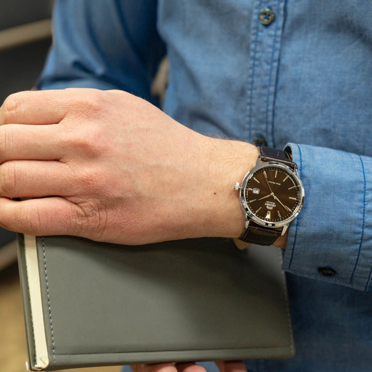 Men's automatic wristwatch with brown dial and dark leather strap.