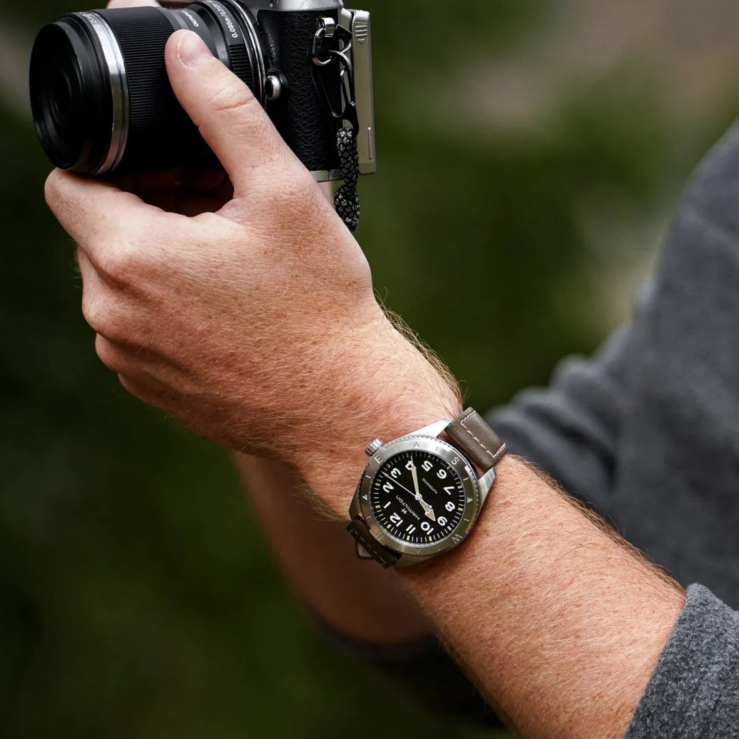 Hamilton automatic wrist watch on arm with black dial and brown leather strap