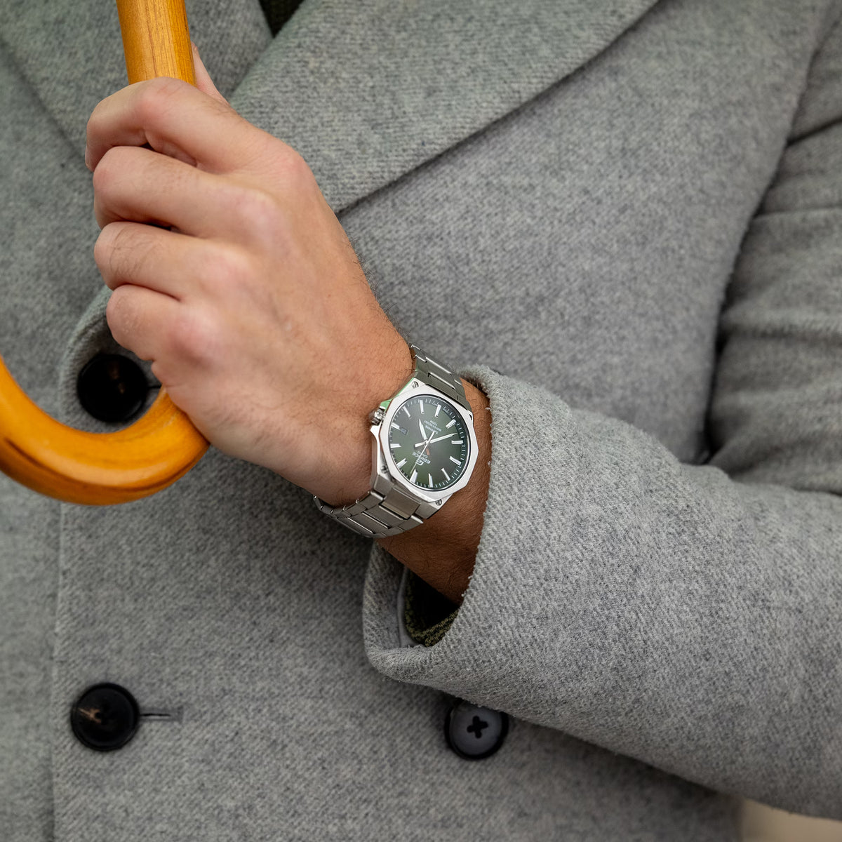 Close-up wrist view of the Casio Edifice EFR-S108D-3AVUEF green watch paired with a grey coat