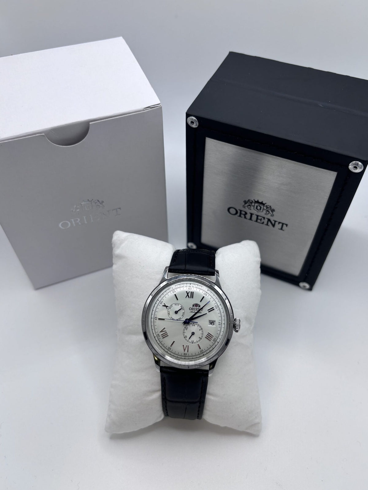 Men's automatic leather watch with white dial, black strap, and Roman numeral markers