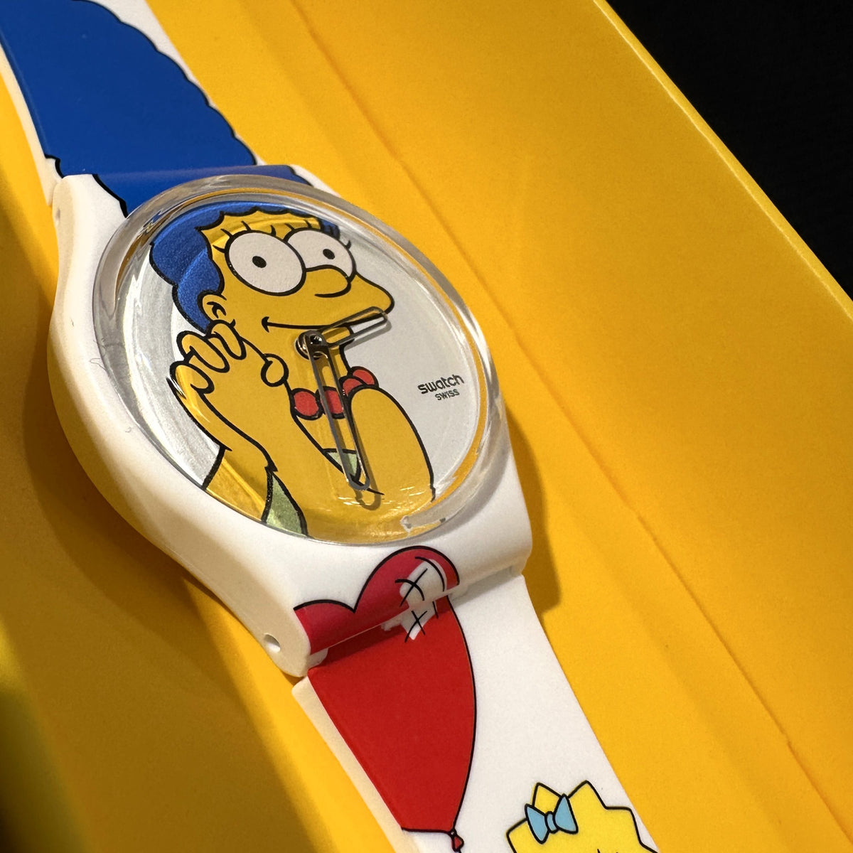 Close-up of Swatch ladies watch face with Homer Simpson illustration and red heart on strap
