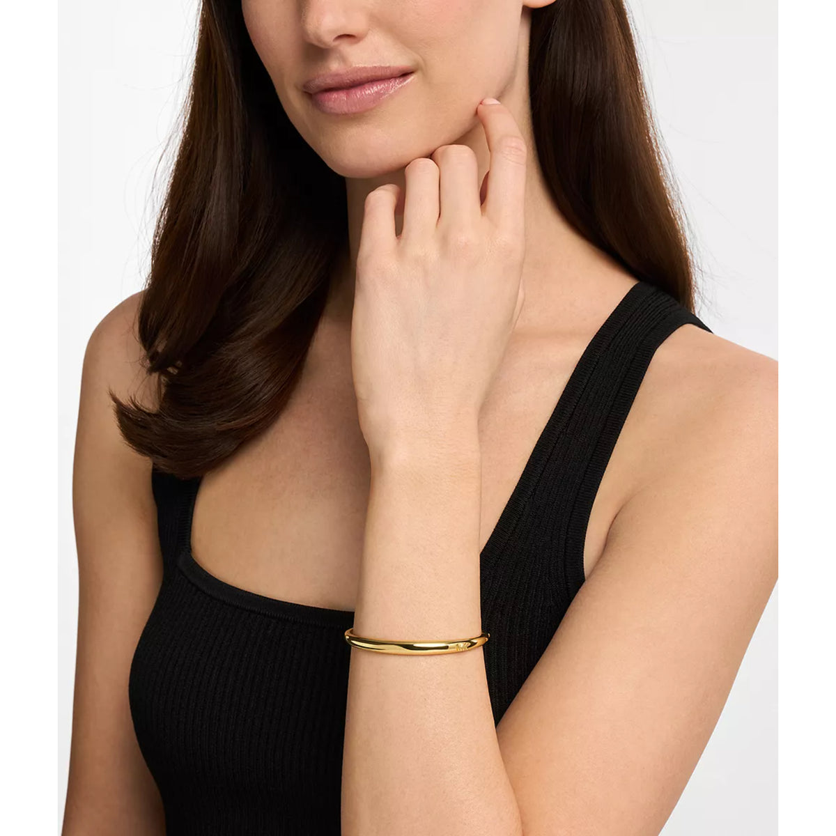 Gold-tone bangle bracelet worn on wrist, slim profile with engraved MK mark