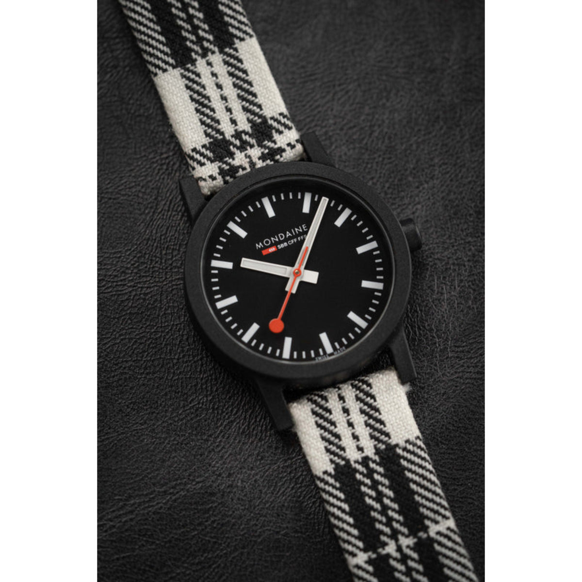 Ladies quartz wristwatch with black dial, white markers, and black-and-white tartan strap